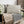 Load image into Gallery viewer, Decorative pillows and blankets on a wooden bench with a wicker basket and flowers in the background.
